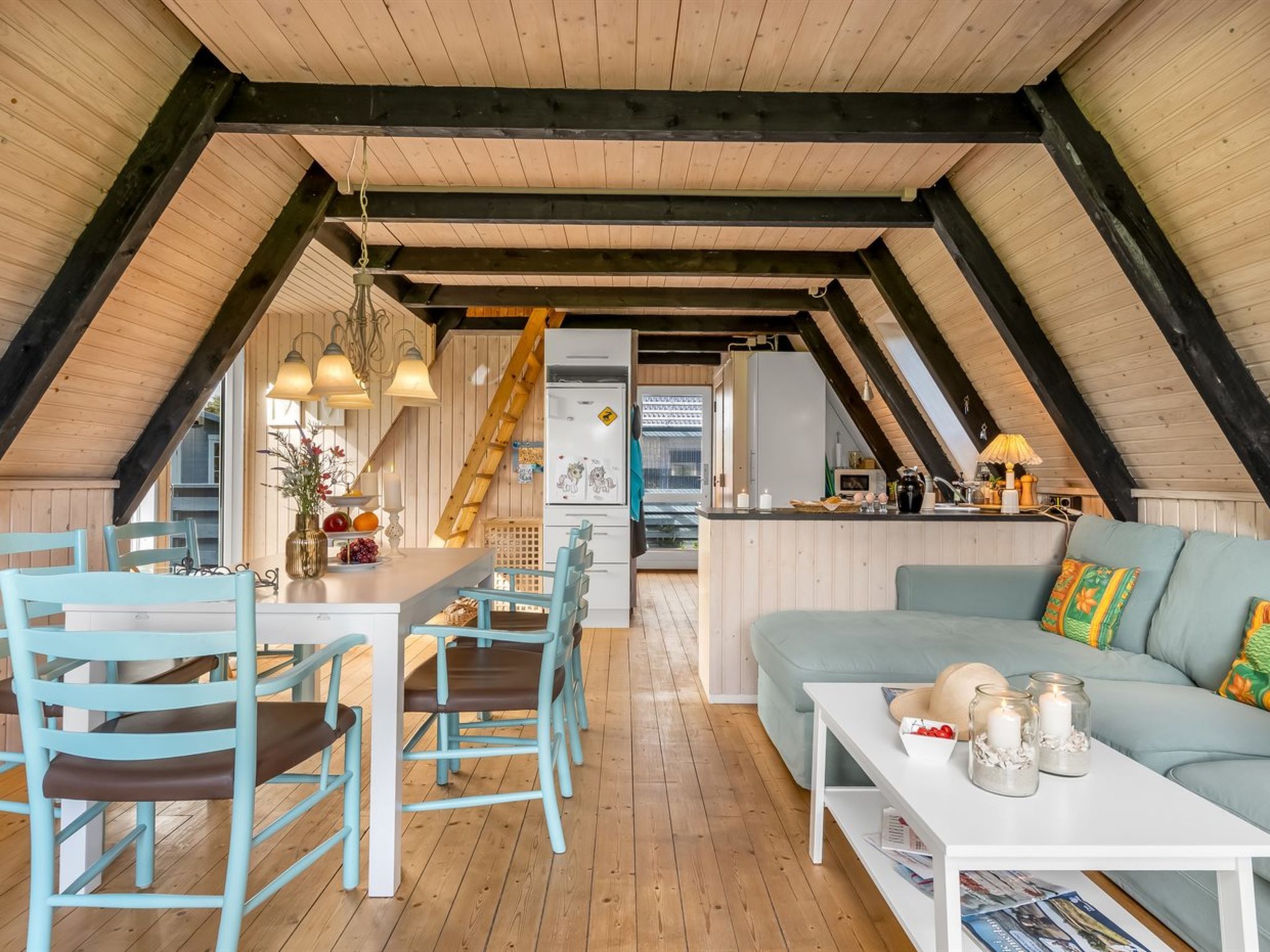 Una habitación acogedora tipo buhardilla con comedor, sofá y zona de cocina.