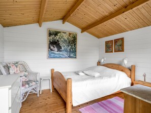 A bedroom with a wooden bed, a white chair, a small table, and a painting on the wall. - "Annalia" - 400m from the sea by Interhome (Hadsund)