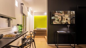 A modern kitchen with a dining area, a green accent wall, and a cityscape painting. - MICELI EXCLUSIVE SUITE (Palermo)