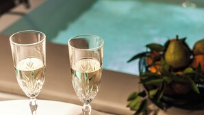 Two glasses of water on a table with a fruit arrangement in the background. - MICELI EXCLUSIVE SUITE (Palermo)