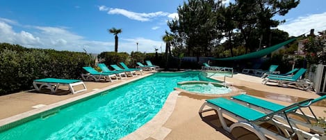 Una piscina con varias sillas de descanso y una palmera.