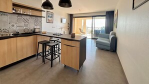 Eine moderne Küche mit Holzausstattung, einer zentralen Kochinsel mit Barhocker, Pendelleuchten und Blick auf einen Balkon.