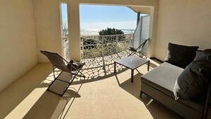 Ein Balkon mit Meerblick, einer Couch und zwei Stühlen.