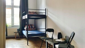 A room with a bunk bed, a small table with chairs, a radiator, and a window with curtains. - Hostel Uno (Kraków)