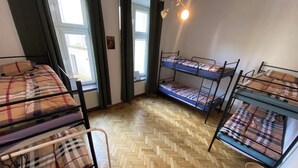 A dormitory room with bunk beds, a herringbone-patterned wooden floor, and a small round table. - Hostel Uno (Kraków)