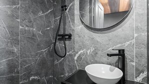 A bathroom with a black sink, a round mirror, and a shower with a handheld hose. - Renovated duplex in central Val Thorens with wifi (Val Thorens)