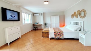 Un dormitorio con cama, escritorio, silla, televisor y armario.
