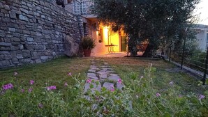 Un muro de piedra y un sendero que conduce a una entrada cálidamente iluminada.
