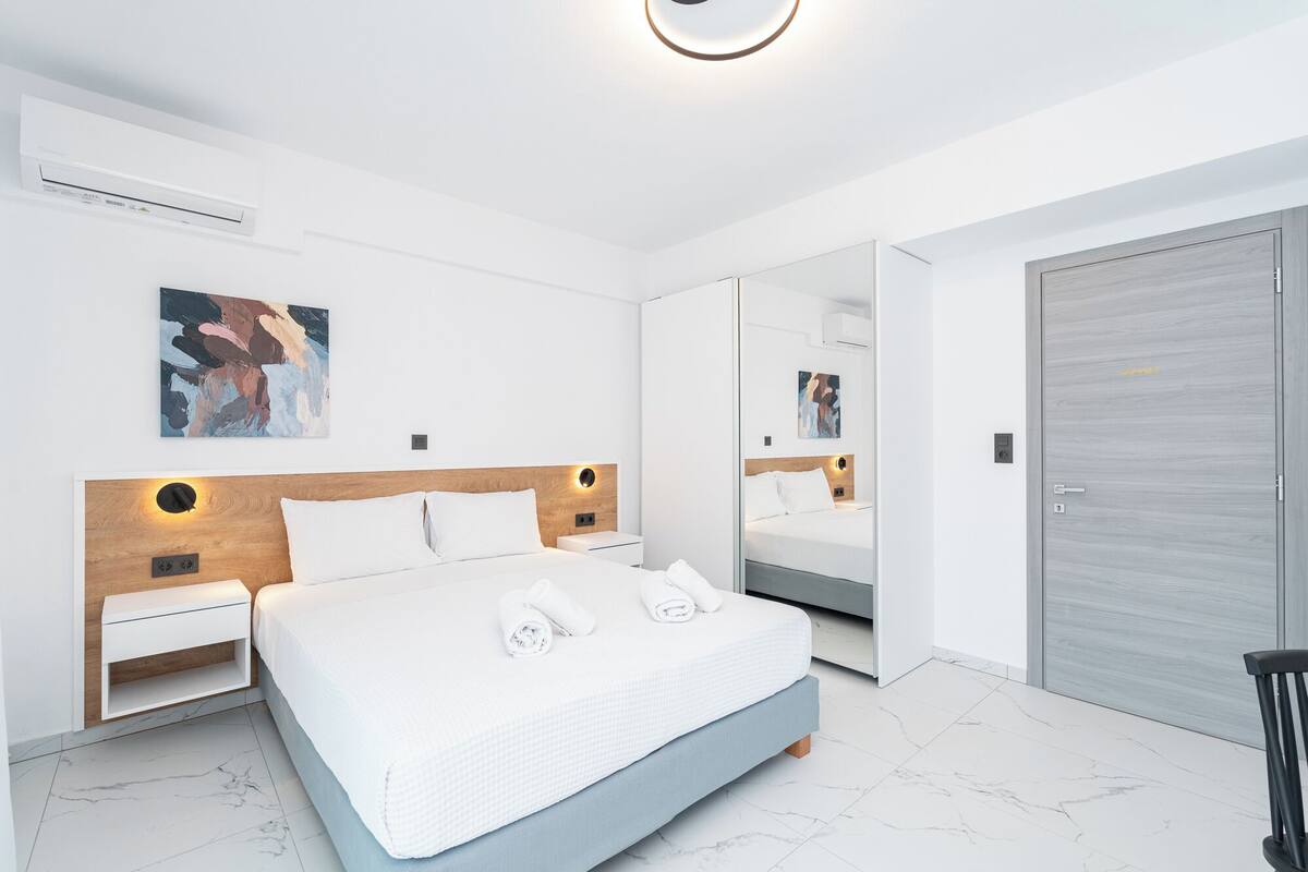 Une chambre à coucher moderne avec un grand lit, des tables de chevet, une armoire et un miroir.