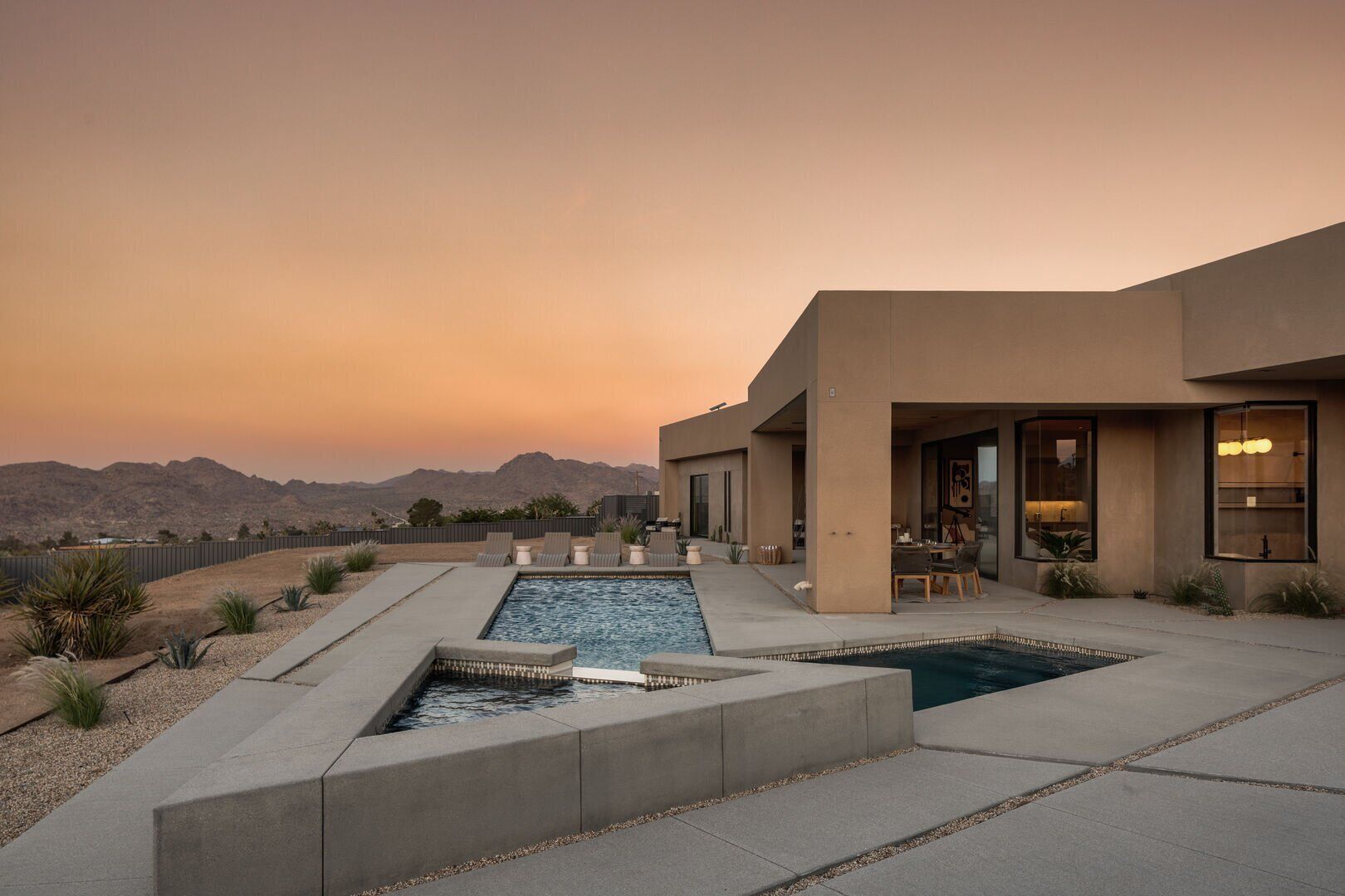 A modern house with a swimming pool, outdoor seating, and a view of mountains.
