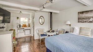 Una habitación de hotel con cama, escritorio, silla, mesita y televisor.
