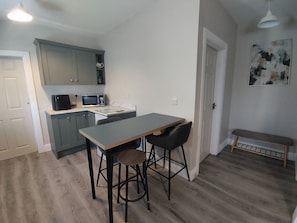 A compact kitchen with a microwave, a small dining table, and bar stools. - Apartment - Sleeps 4 - Near Aran Islands - Parking (Inverin)