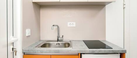 Una cocina compacta con lavamanos, encimera y un refrigerador blanco.