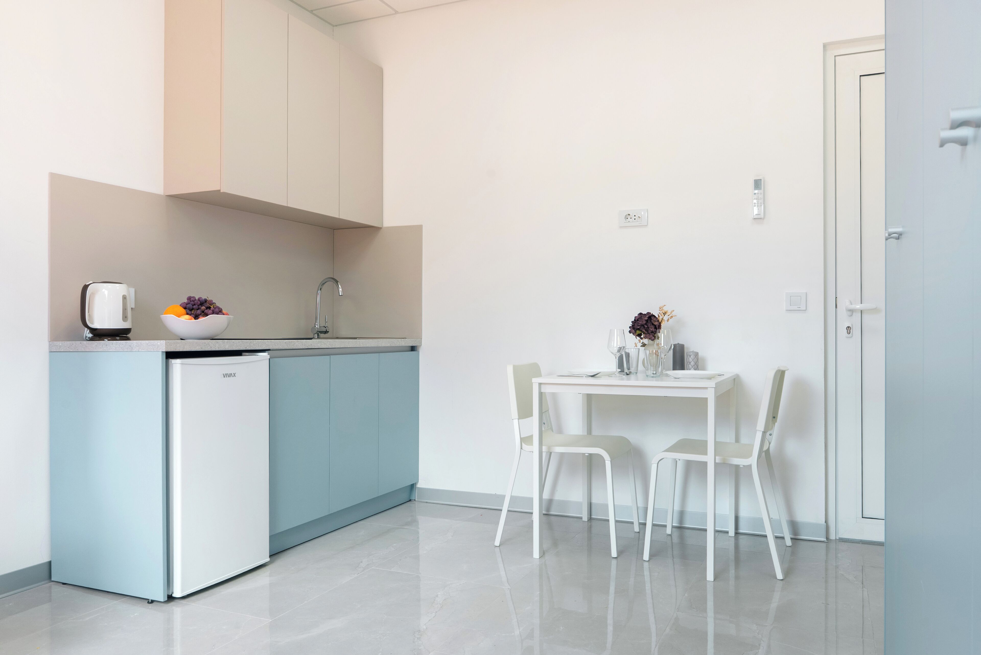 Eine moderne Küche mit integriertem Kühlschrank, Spüle und einem Essbereich mit Tisch und Stühlen.