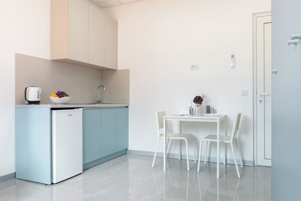 A modern kitchen with a built-in refrigerator, a sink, and a dining area with a table and chairs.