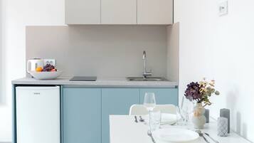 A modern kitchen with a built-in fridge, a dining table with chairs, and a vase with flowers on the table.