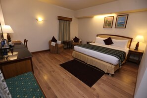 A hotel room with a bed, bedside tables, a desk, and a chair. - Embassy Inn (Karachi)