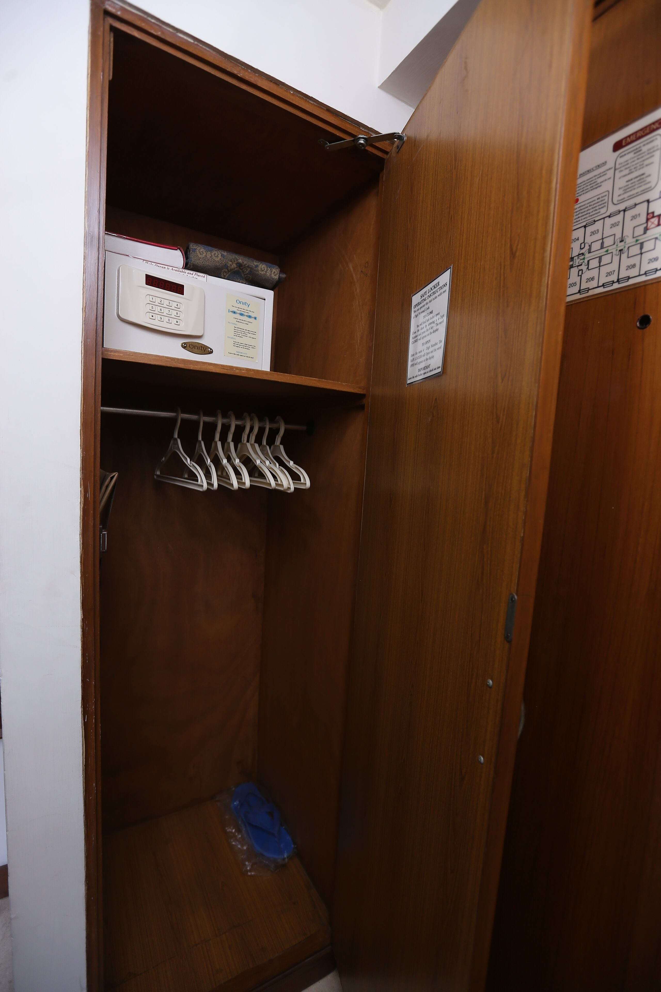 A wooden closet with a shoe rack, a small shelf with a box, and a floor mat.