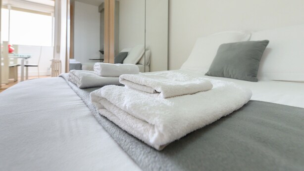 A neatly made bed with folded white towels and a grey blanket. - 2 Bedroom Apartment with City Views - Comfort and Style in Madrid (Madrid)