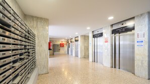 A clean, modern hallway with a row of elevators and a fire extinguisher on the wall. - 2 Bedroom Apartment with City Views - Comfort and Style in Madrid (Madrid)