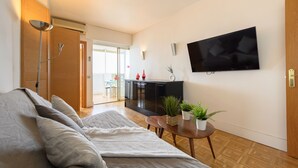 A modern living room with a sofa, a TV mounted on the wall, and a small table with plants. - 2 Bedroom Apartment with City Views - Comfort and Style in Madrid (Madrid)