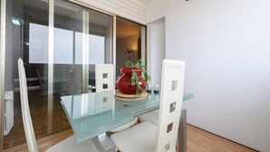 A modern dining area with a glass table, white chairs, and a decorative red vase with greenery. - 2 Bedroom Apartment with City Views - Comfort and Style in Madrid (Madrid)