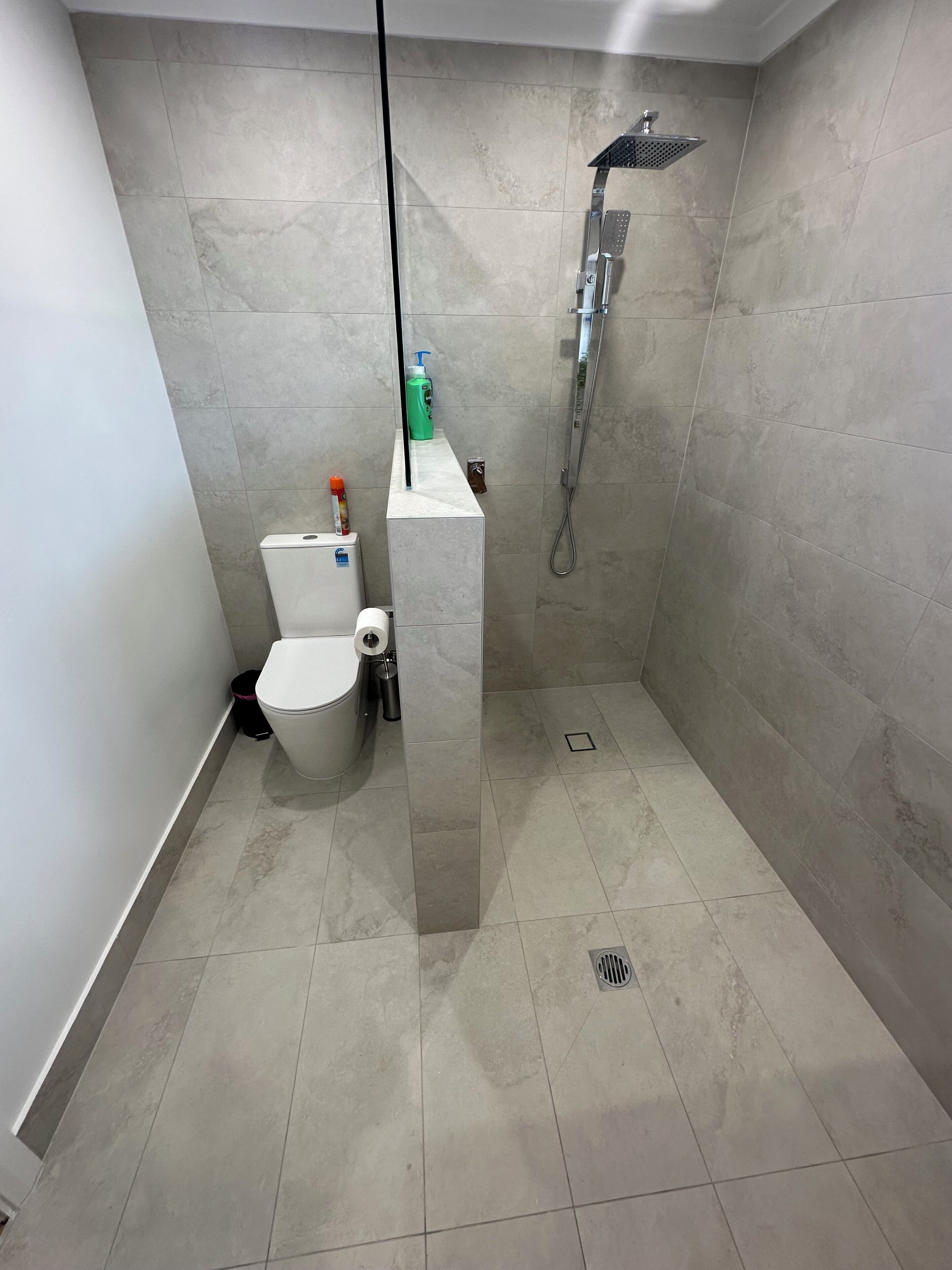 Uma casa de banho moderna com sanita, chuveiro e lavatório.