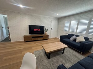 Familie appartement | Woonruimte | Een 65-inch smart-tv met digitale zenders, Netflix en streamingdiensten