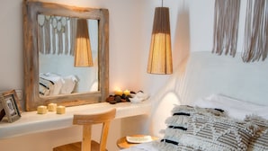 Ein Schlafzimmer mit einem spiegelnden Holzbettrahmen, einem Nachttisch mit Kerzen, einer Pendelleuchte und einem Bett mit gemusterten Betttextilien.