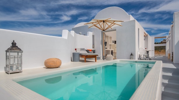 Ein moderner Poolbereich mit einem klaren, blauen Pool, weißen Wänden und einem minimalistischen Design.