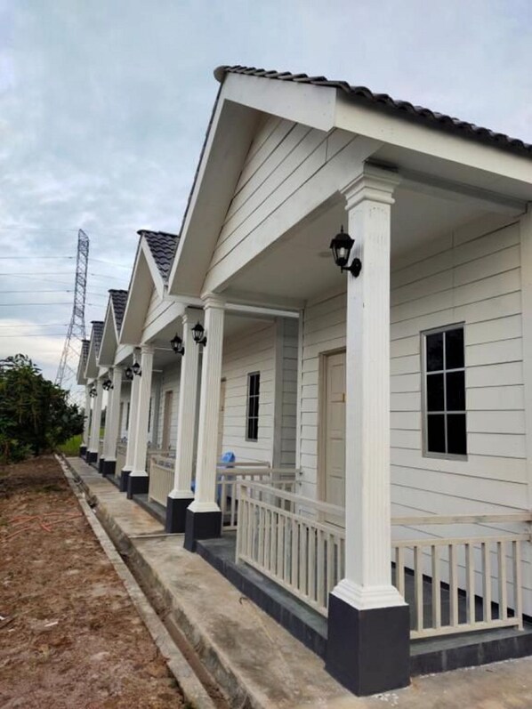 A row of white houses with a covered porch and black railings. - D Paddy HR Guest House (Arau)