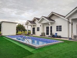 A residential property with a swimming pool, a covered patio, and a well-maintained lawn. - D Paddy HR Guest House (Arau)
