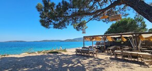 A beachside restaurant with outdoor seating, overlooking the sea.