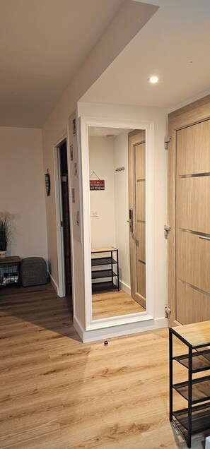 A room with a wooden floor, a white door, and a black metal shelf.