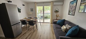 A compact living space with a kitchenette, dining area, and a sofa with cushions.