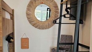 A compact room with a bunk bed, a round mirror, and a small shelf with a box.