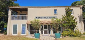 A two-story building with a sign reading 'Fiori Di Cala Rosso'. There are two windows on the ground floor and a balcony on the upper floor.