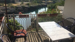 A balcony with a table and chairs, overlooking a river and a residential area. - Charming 4-bedroom house with WiFi and AC in lovely Mostar (Mostar)