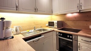 A compact kitchen with white cabinets, a microwave, a coffee maker, and a sink. - Apartment in Winterberg Near Ski Lift (Winterberg)