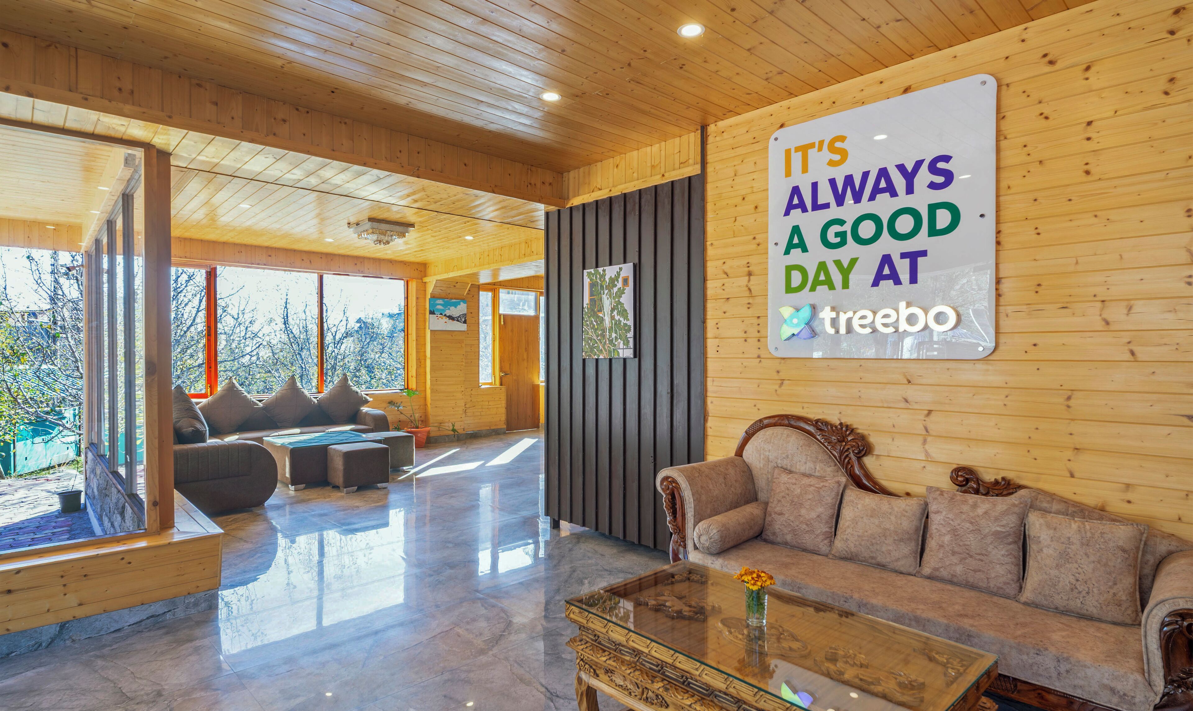 A spacious room with a wooden ceiling and walls, a large window, a sofa, a coffee table, and a sign on the wall.