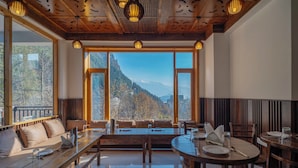 Comedor con vista a la montaña, muebles de madera e iluminación colgante.