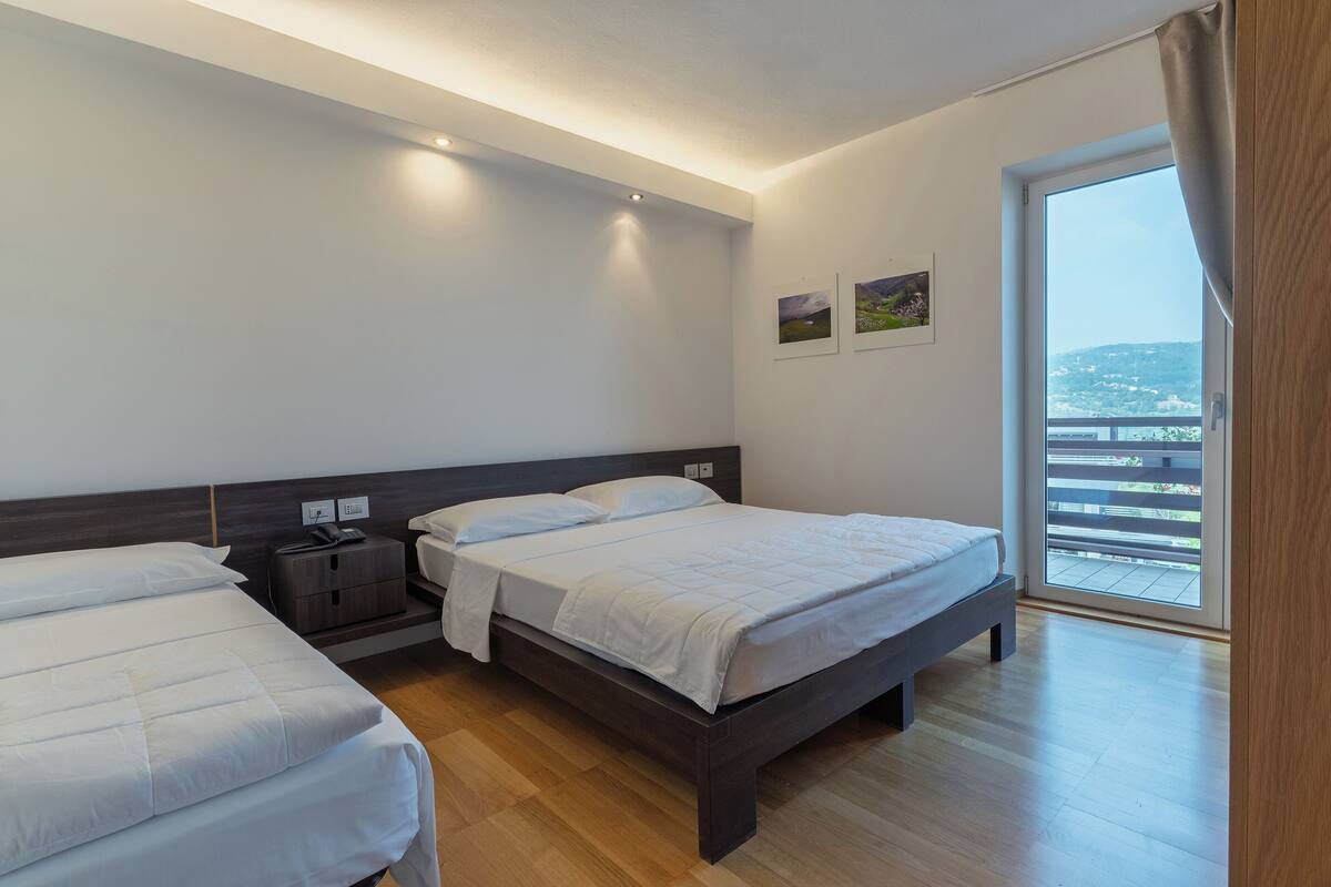 A modern bedroom with a large bed, bedside tables, and a view of a balcony.