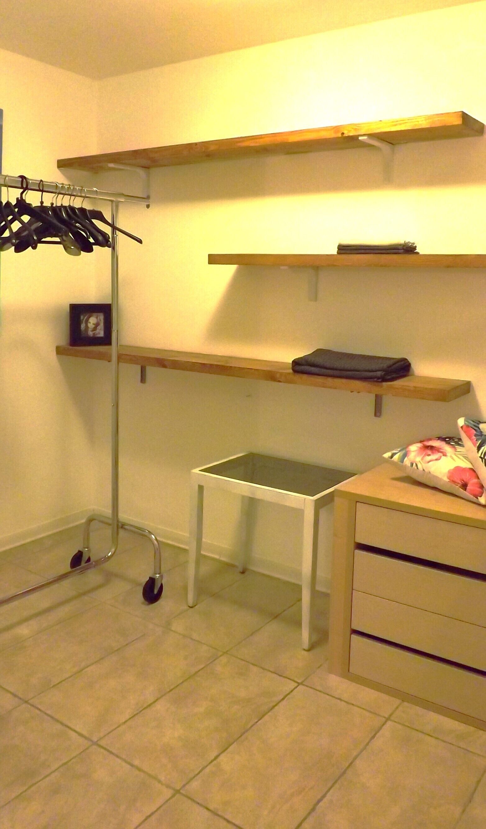 A room with a white desk, a metal cart with wheels, and wooden shelves.