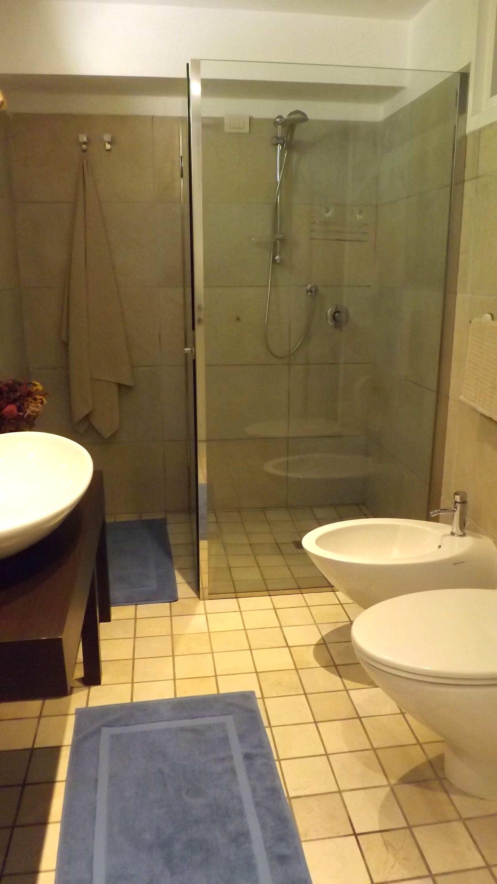 A bathroom with a glass-enclosed shower, two sinks, and a toilet.