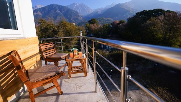 Een balkon met houten meubels en een tafel, met uitzicht op een bergachtig landschap.