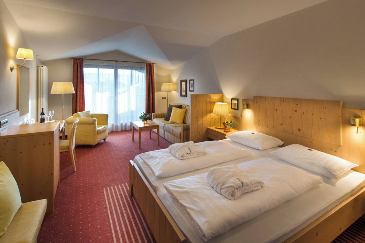 Une chambre d’hôtel avec deux lits, un bureau, une chaise et une petite table.