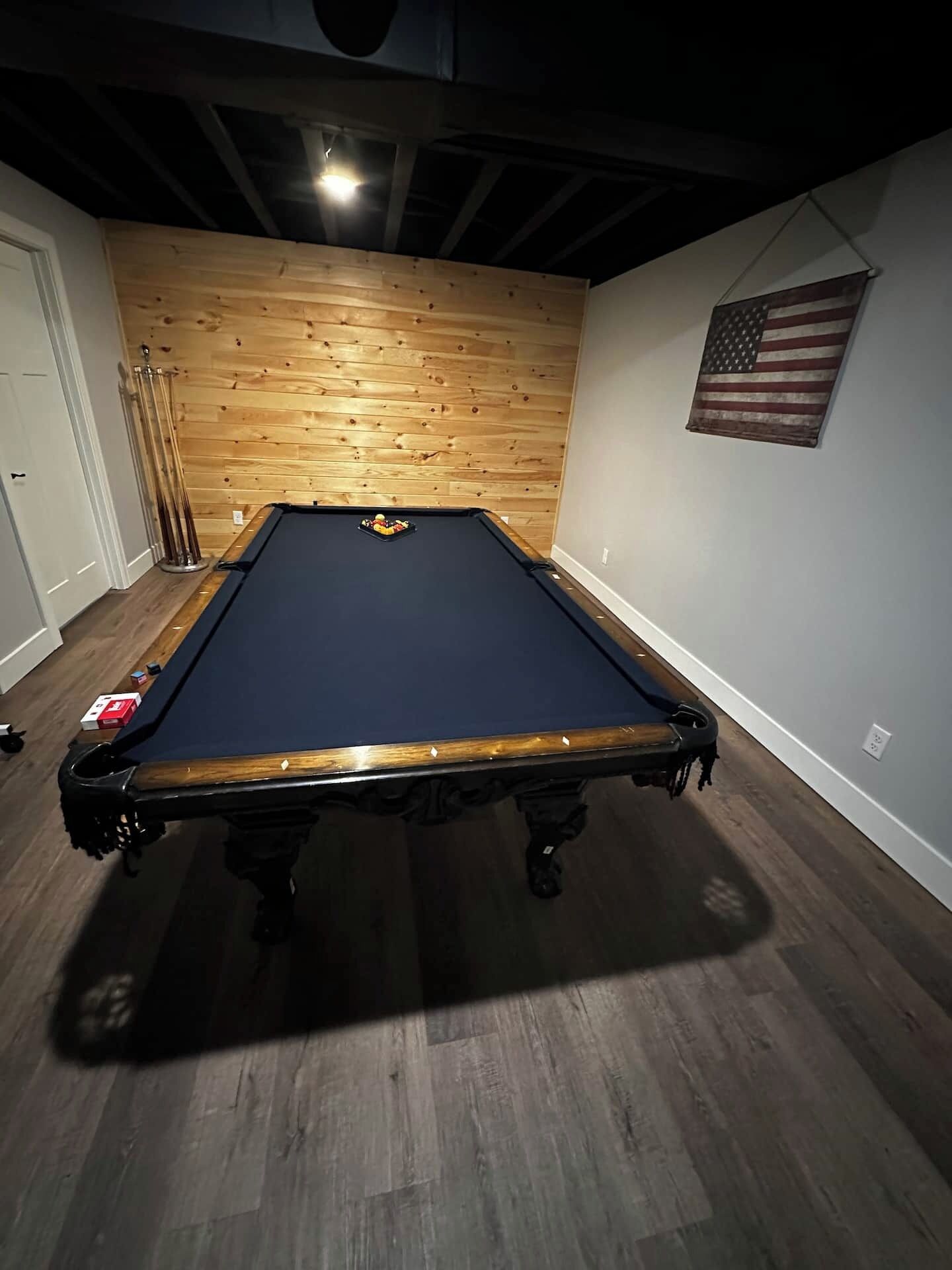 A pool table in a room with wooden walls and a ceiling light.