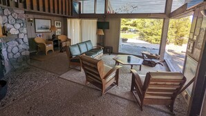Un interior acogedor y rústico con pared de piedra, muebles de madera y un amplio ventanal con vistas al exterior.