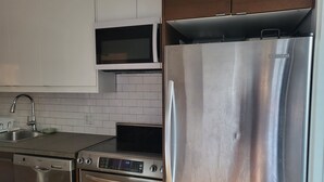 A modern kitchen with stainless steel appliances, including a refrigerator, oven, and microwave. - Superb apartment with terrace near metro rosemont (Montréal)