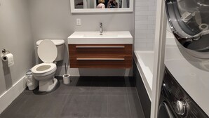 A modern bathroom with a toilet, sink, and mirror. - Superb apartment with terrace near metro rosemont (Montréal)